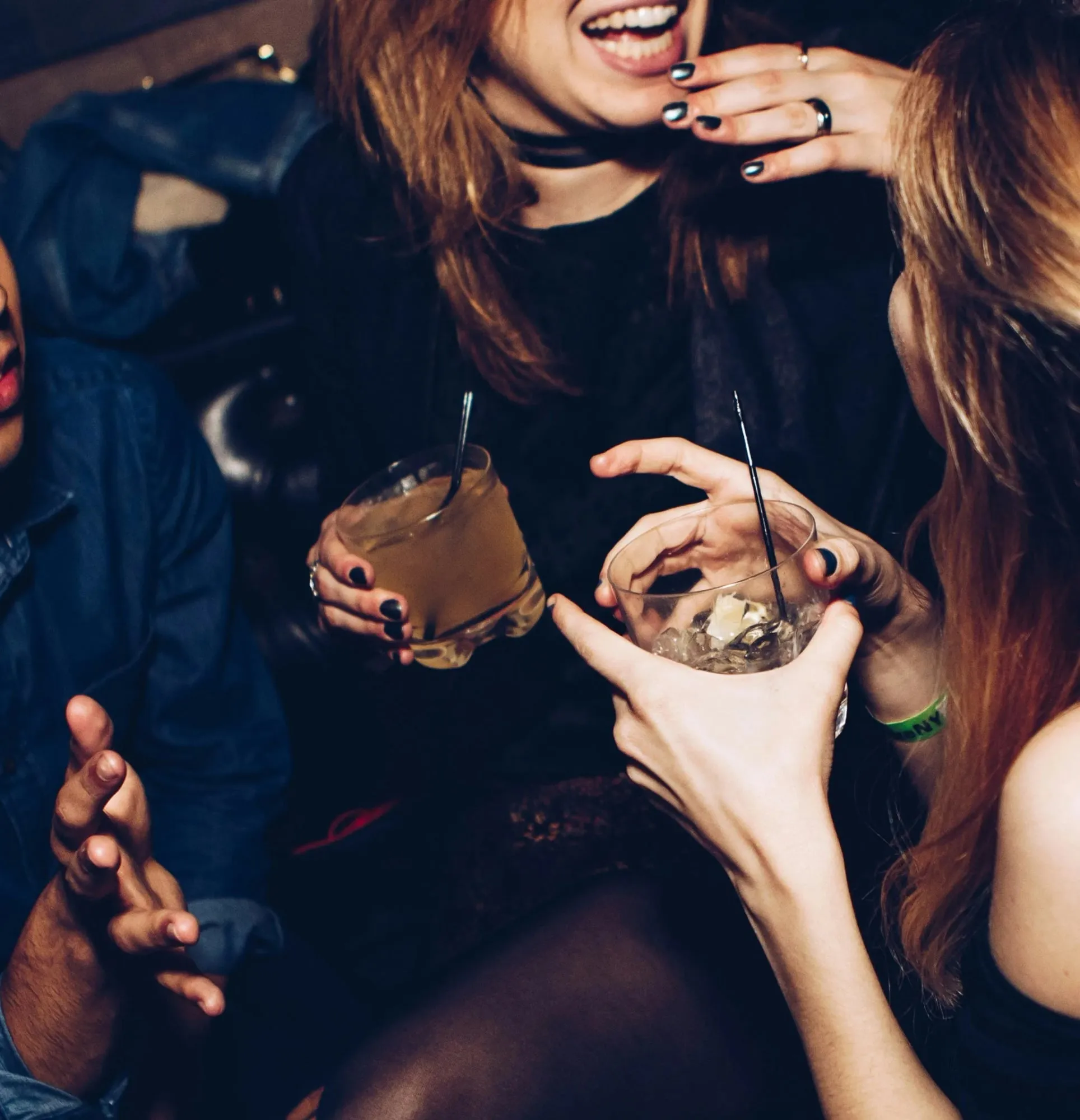 Friends laughing and sharing cocktails at a party.
